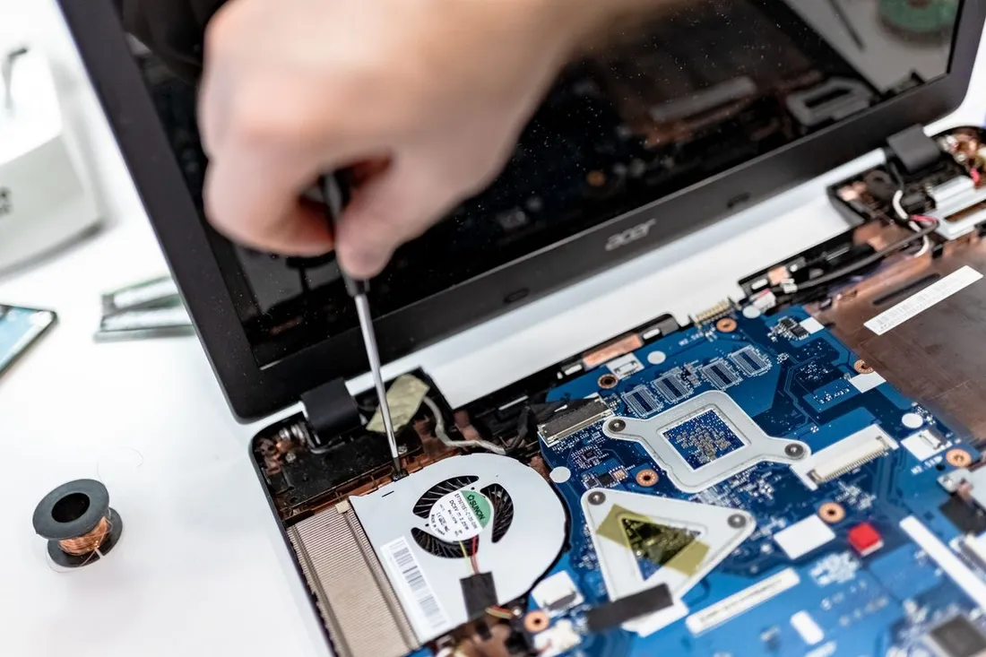 Technician repairing an open laptop with a screwdriver
